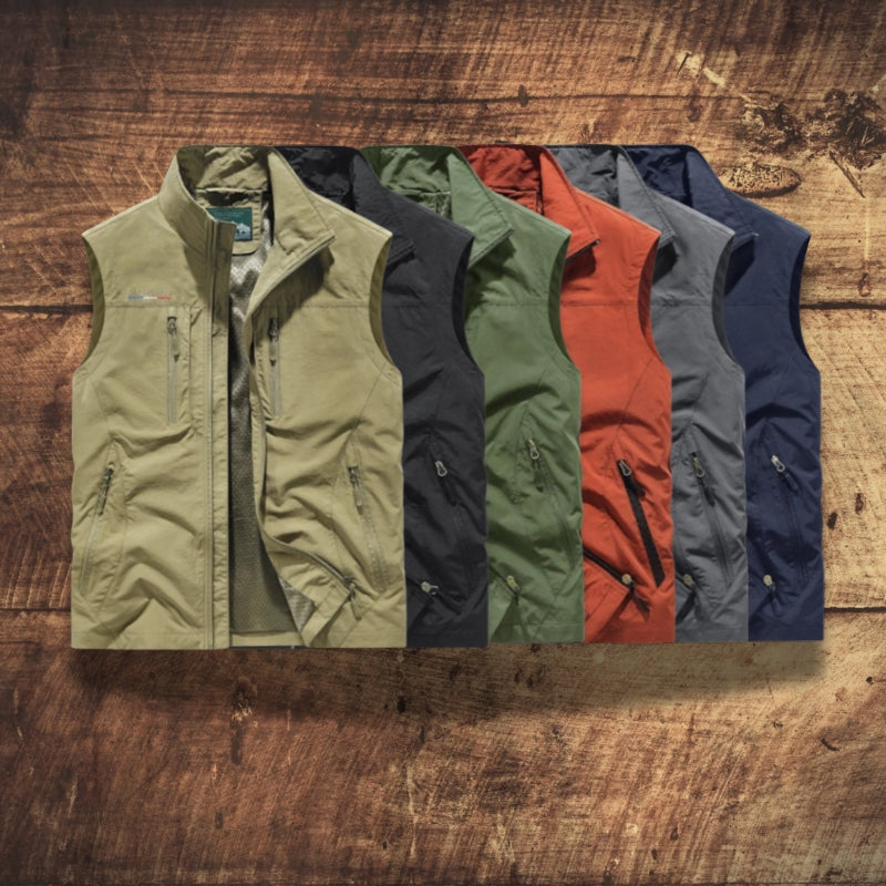 Five lightweight zip-front vest jackets are arranged in a fan shape on a rustic wooden surface. The vests come in olive green, charcoal gray, forest green, rust orange, and navy blue.