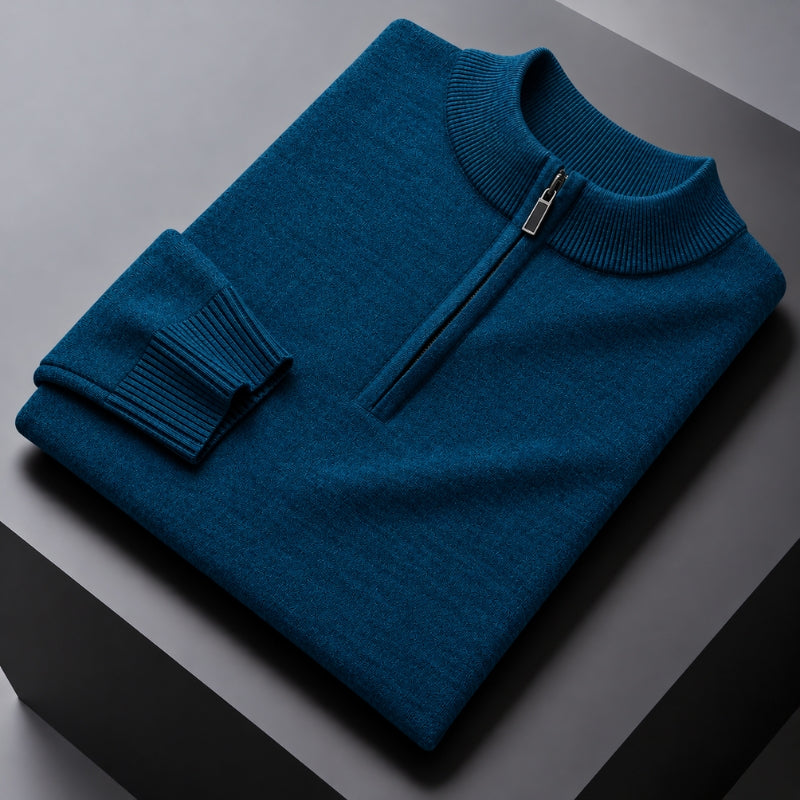 A folded teal blue half-zip knit sweater with a ribbed mock neck and cuff, displayed on a dark gray geometric surface.