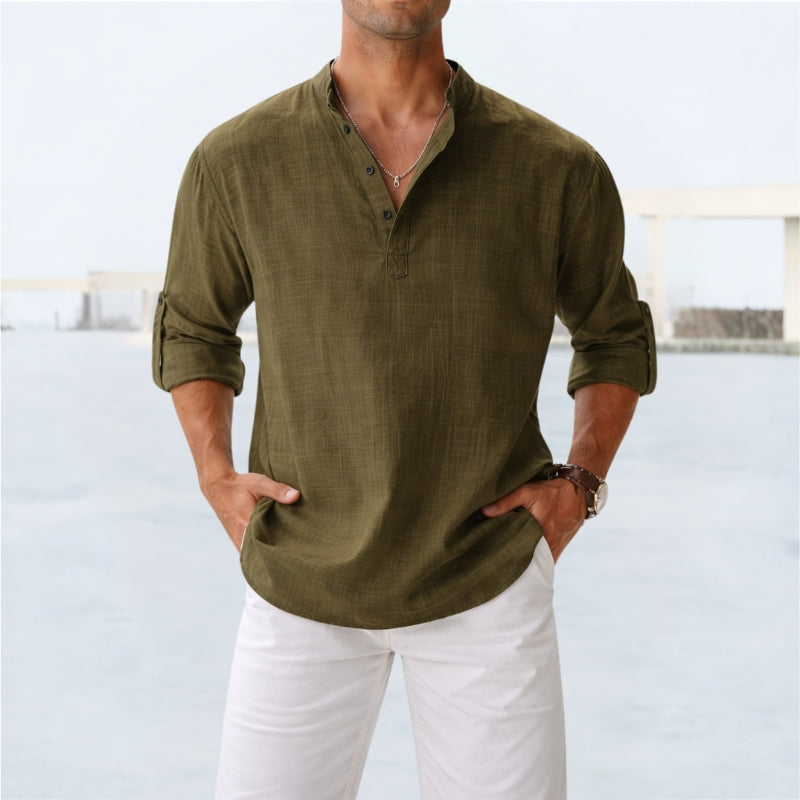 Man wearing an army green long-sleeve shirt and white pants against a light background