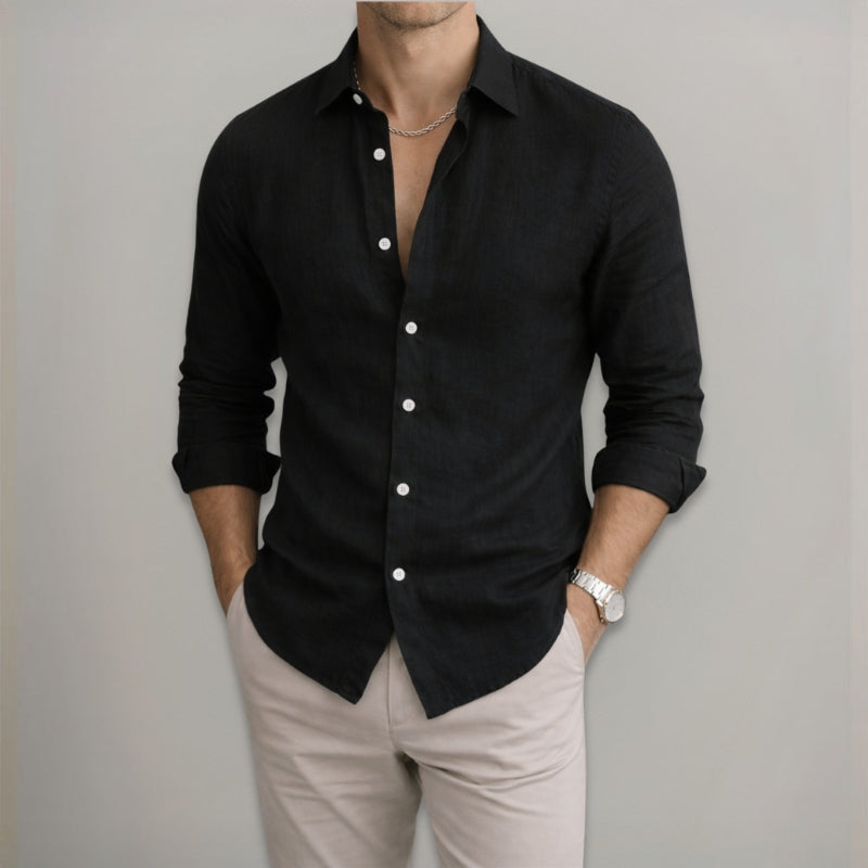 Man wearing a black button-up shirt and beige pants against a gray background