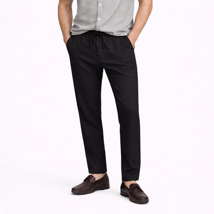 Person wearing black linen pants and brown shoes on a white background