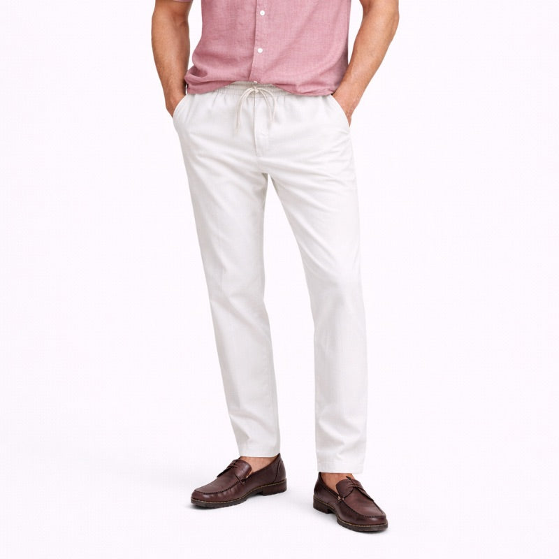 Person wearing white linen pants and a pink shirt on a white background