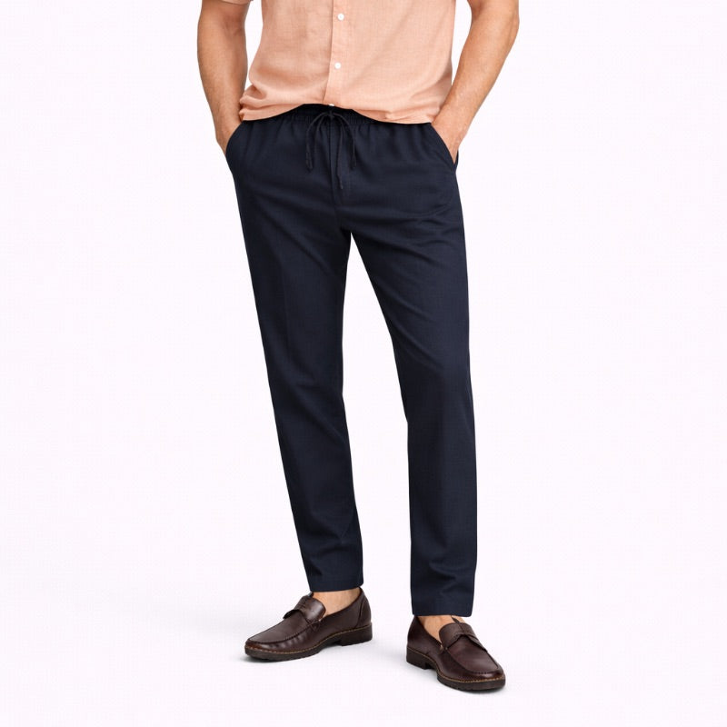 Person wearing navy linen pants and brown shoes on a white background