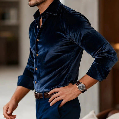 Man wearing a dark blue velvet shirt with a blurred indoor background