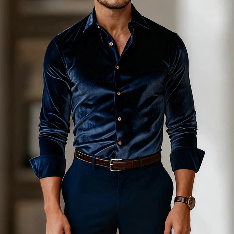 Man wearing a dark blue velvet shirt with gold buttons and dark pants.