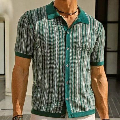 Person wearing a green and white patterned shirt with a blurred background