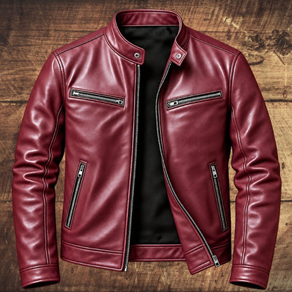 A burgundy leather jacket with silver zippers and a black interior lining, displayed flat against a rustic wooden plank background.