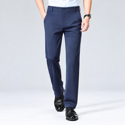 A man wearing navy blue dress pants, a white shirt, and black dress shoes, shown from the waist down against a light gray studio background.