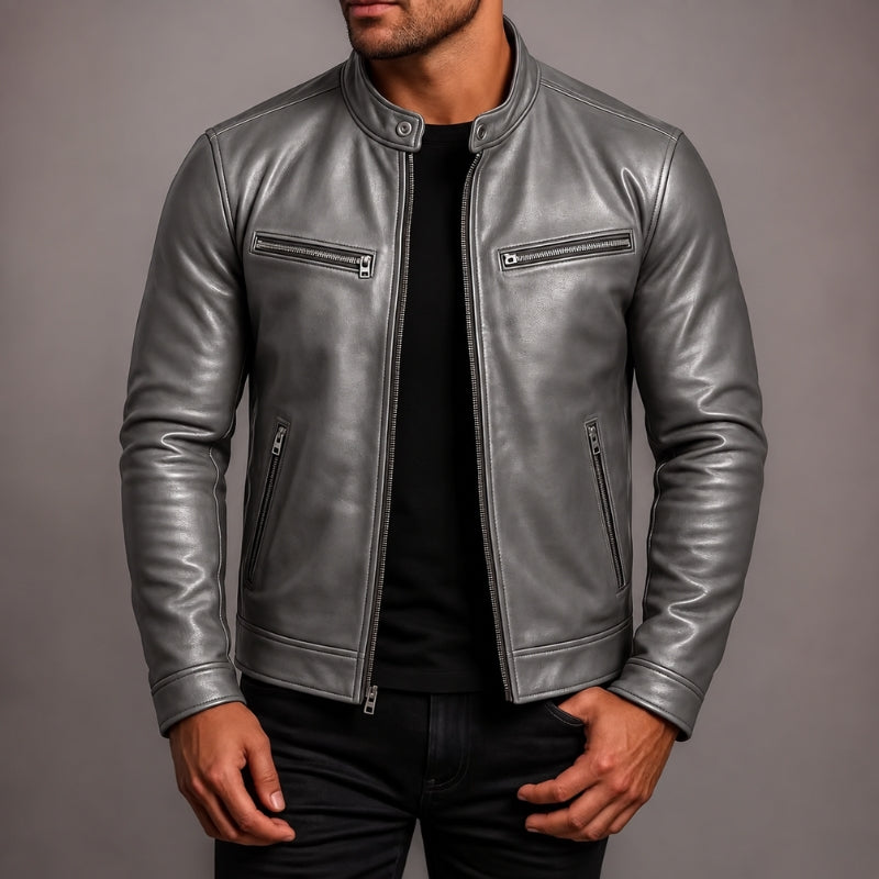 A man wearing a metallic silver leather jacket over a black shirt and black pants, shown from the chin down against a plain gray studio background.