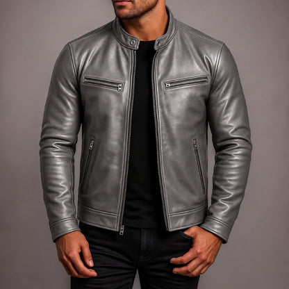 A man wearing a metallic silver leather jacket over a black shirt and black pants, shown from the chin down against a plain gray studio background.