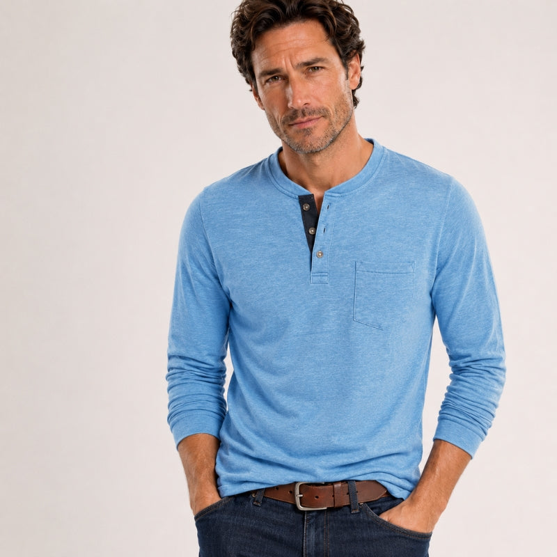 Man wearing a blue long-sleeve henley shirt on a light gray background