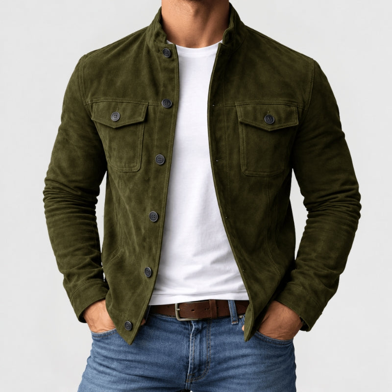 A man wearing an olive green corduroy jacket over a white t-shirt and blue jeans, shown from the neck down against a light gray background.