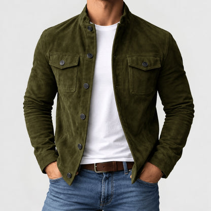 A man wearing an olive green corduroy jacket over a white t-shirt and blue jeans, shown from the neck down against a light gray background.