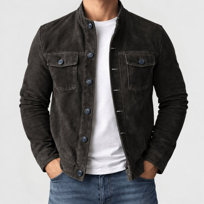 A man wearing a dark brown suede jacket over a white t-shirt and blue jeans, shown from the neck down against a light gray background.
