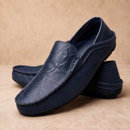 Pair of navy blue loafers on a beige background