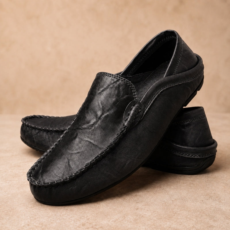 Pair of black leather loafers on a beige background