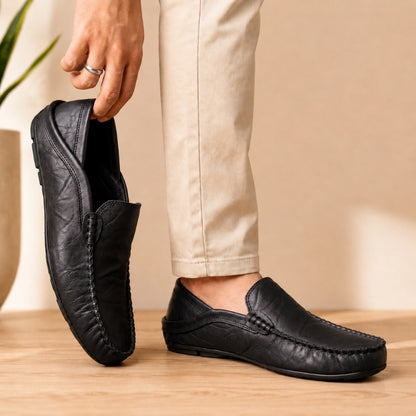 Black leather loafers being worn with a neutral background