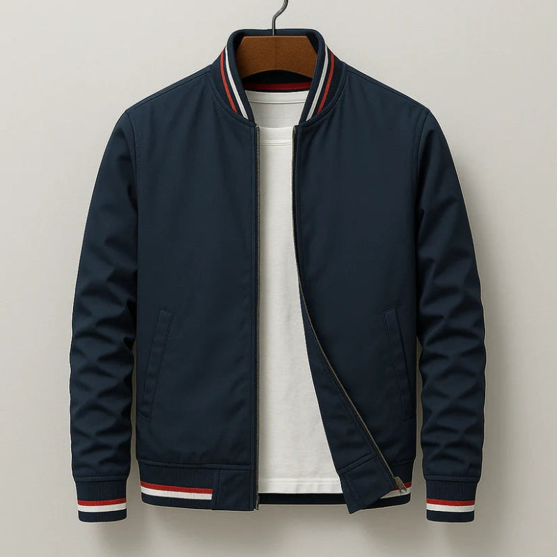 A navy blue zip-up bomber jacket with red and white striped ribbed trim on the collar, cuffs, and hem, layered over a white t-shirt and hanging on a wooden hanger against a light gray background.