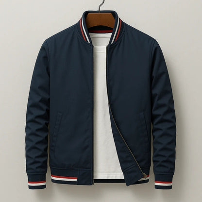 A navy blue zip-up bomber jacket with red and white striped ribbed trim on the collar, cuffs, and hem, layered over a white t-shirt and hanging on a wooden hanger against a light gray background.