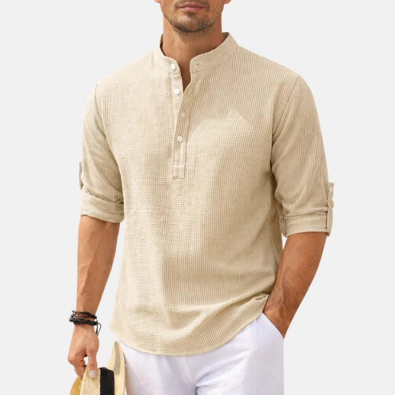 Man wearing a beige textured shirt with rolled-up sleeves on a white background