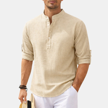 Man wearing a beige textured shirt with rolled-up sleeves on a white background