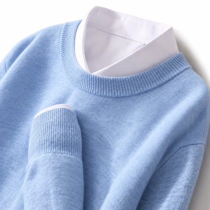 A light blue knit sweater layered over a white collared shirt, shown in a close-up studio shot against a white background.
