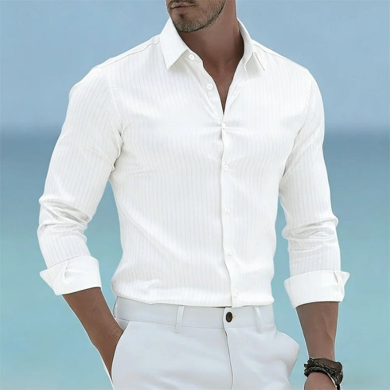 Man wearing a white button-up shirt and light-colored pants against a blue background