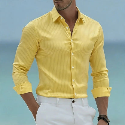 Man wearing a yellow shirt with rolled-up sleeves against a blue sky background