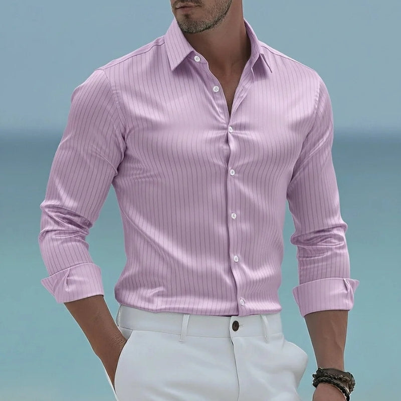 Man wearing a pink striped shirt and white pants against a blue sky.