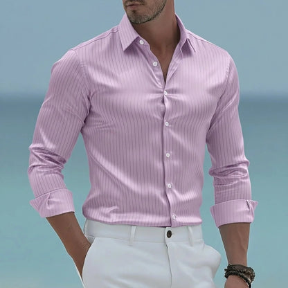 Man wearing a pink striped shirt and white pants against a blue sky.