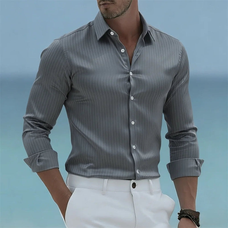 Man wearing a gray striped shirt with rolled-up sleeves against a blue background