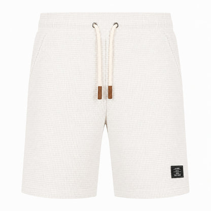 Off-white waffle-knit shorts with a cream drawstring and brown tips, shown against a plain white background.