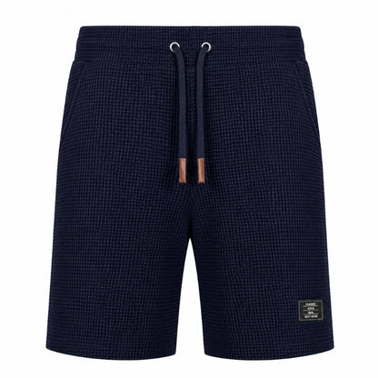 A pair of men's navy blue textured shorts with a matching drawstring and a small brand patch on the lower left leg, shown against a plain white background.