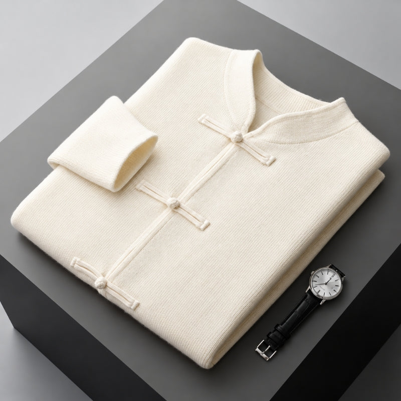 A folded cream-colored knit traditional Chinese-style sweater with a mock neck and button closures, displayed on a dark gray block alongside a wristwatch.