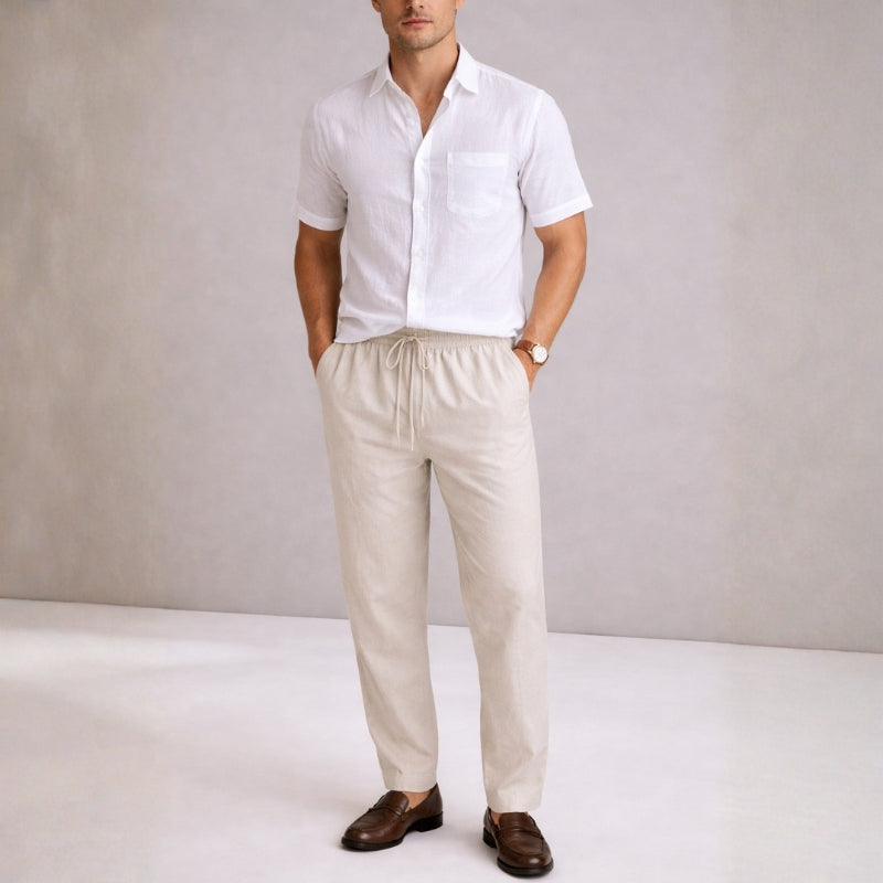 Man wearing a white shirt and beige pants against a plain background