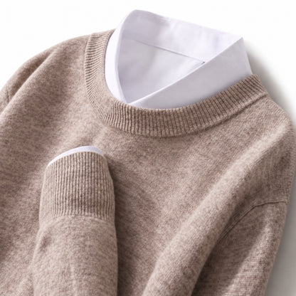 A close-up of a taupe knit sweater layered over a white collared shirt, shown against a clean white background.
