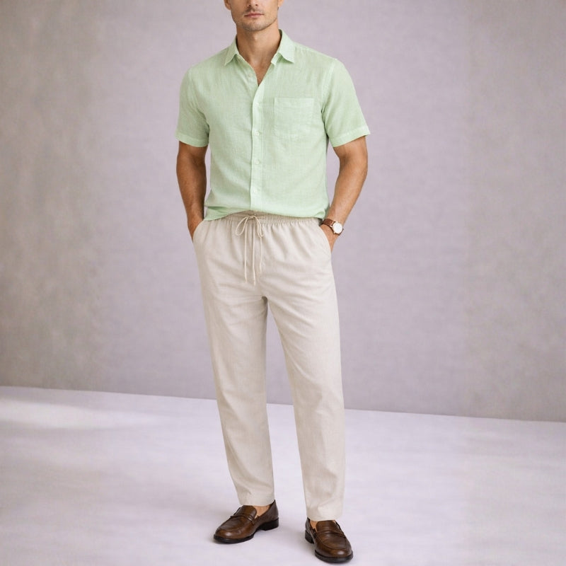 Man wearing a mint green shirt and beige pants against a plain background
