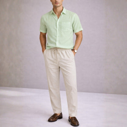 Man wearing a mint green shirt and beige pants against a plain background