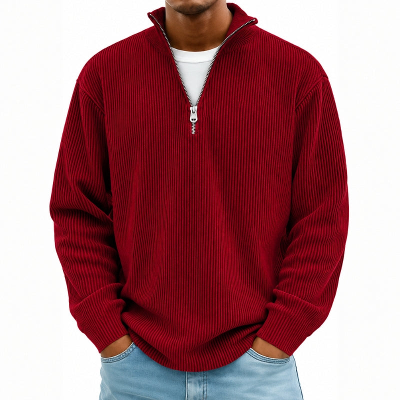 A man wearing a red ribbed knit quarter-zip pullover sweater over a white t-shirt and light blue jeans, shown from the chin down against a plain white background.