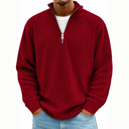 A man wearing a red ribbed knit quarter-zip pullover sweater over a white t-shirt and light blue jeans, shown from the chin down against a plain white background.