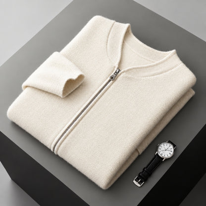 A folded cream-colored zip-up sweater is displayed on a dark gray geometric surface next to a black leather strap wristwatch.