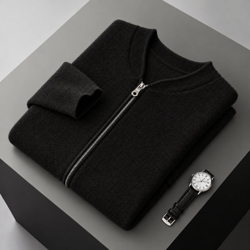 A folded black zip-up sweater or lightweight jacket displayed on a gray geometric pedestal, with a wristwatch placed beside it.