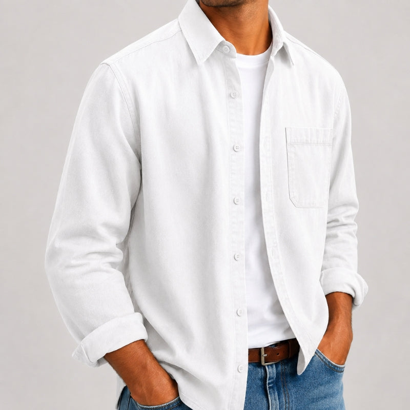 A man wearing a white long-sleeve button-up shirt over a white t-shirt, paired with blue jeans and a brown belt, shown from the neck down against a light gray background.