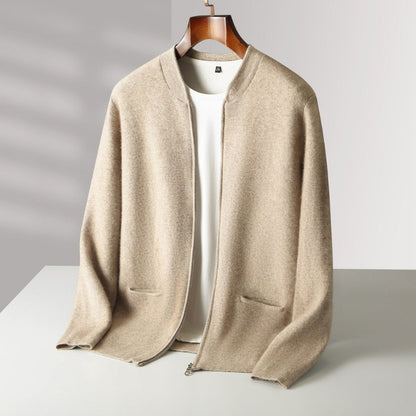 A beige open-front knit cardigan draped over a wooden hanger, layered over a white top. The cardigan has a relaxed fit, long sleeves, and two front patch pockets, shown against a neutral light gray background.