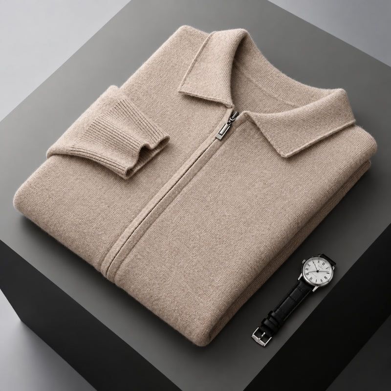 A folded beige knit zip-up sweater with a collar and ribbed cuffs, displayed on a dark gray pedestal alongside a wristwatch.