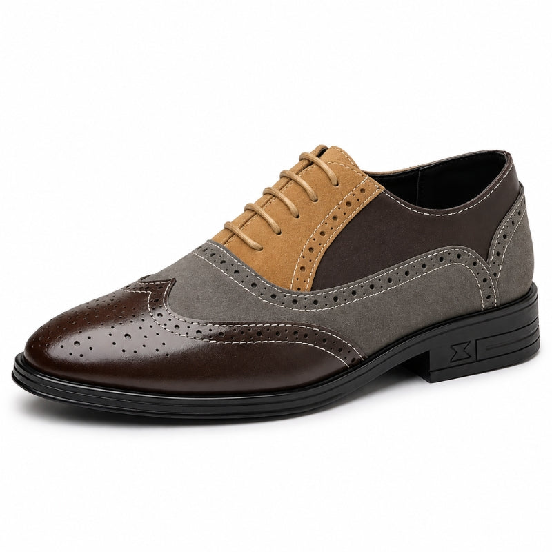 A men's three-tone wingtip oxford shoe with a dark brown brogue toe, a medium gray side panel, and a tan suede V-piece on the vamp, finished with black laces and a black sole.