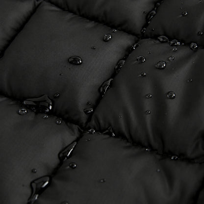 Close-up of a black quilted padded fabric with water droplets beading on the surface, showing the material texture and waterproof finish.
