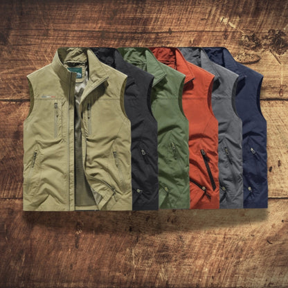 Five lightweight zip-front vest jackets are arranged in a fan shape on a rustic wooden surface. The vests come in olive green, charcoal gray, forest green, rust orange, and navy blue.