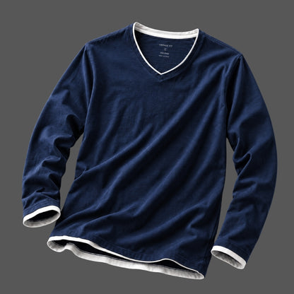 A navy blue long-sleeve V-neck t-shirt with white ribbed trim on the collar, cuffs, and hem, displayed against a solid dark gray background.