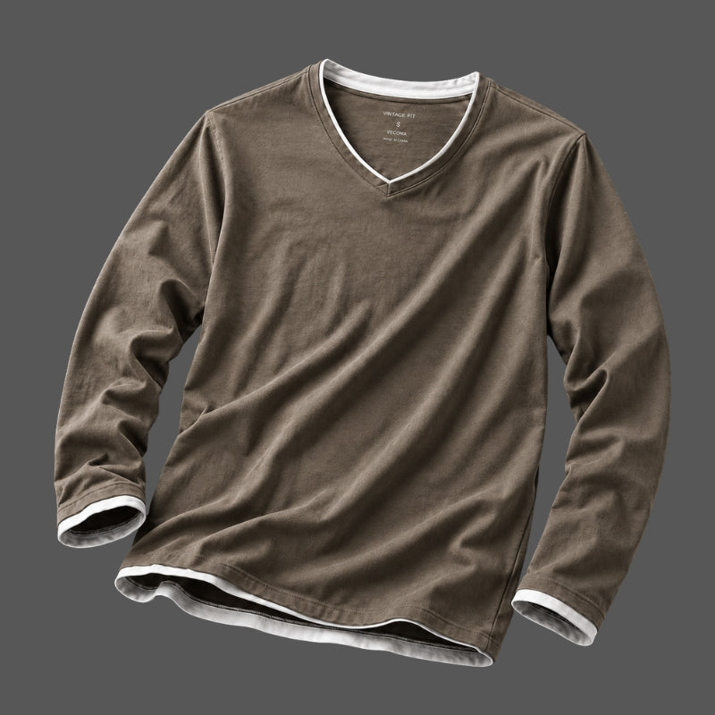A brown long-sleeve V-neck t-shirt with white ribbed trim along the collar, cuffs, and hem, displayed against a solid dark gray background.